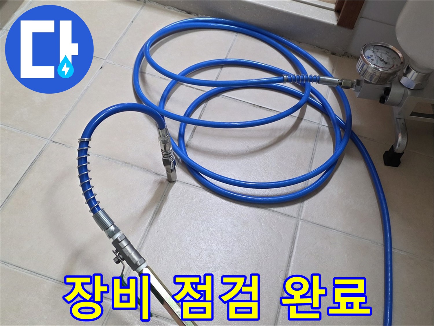 화장실 바닥에 놓인 파란색 공압 호스와 압력 게이지의 모습입니다.