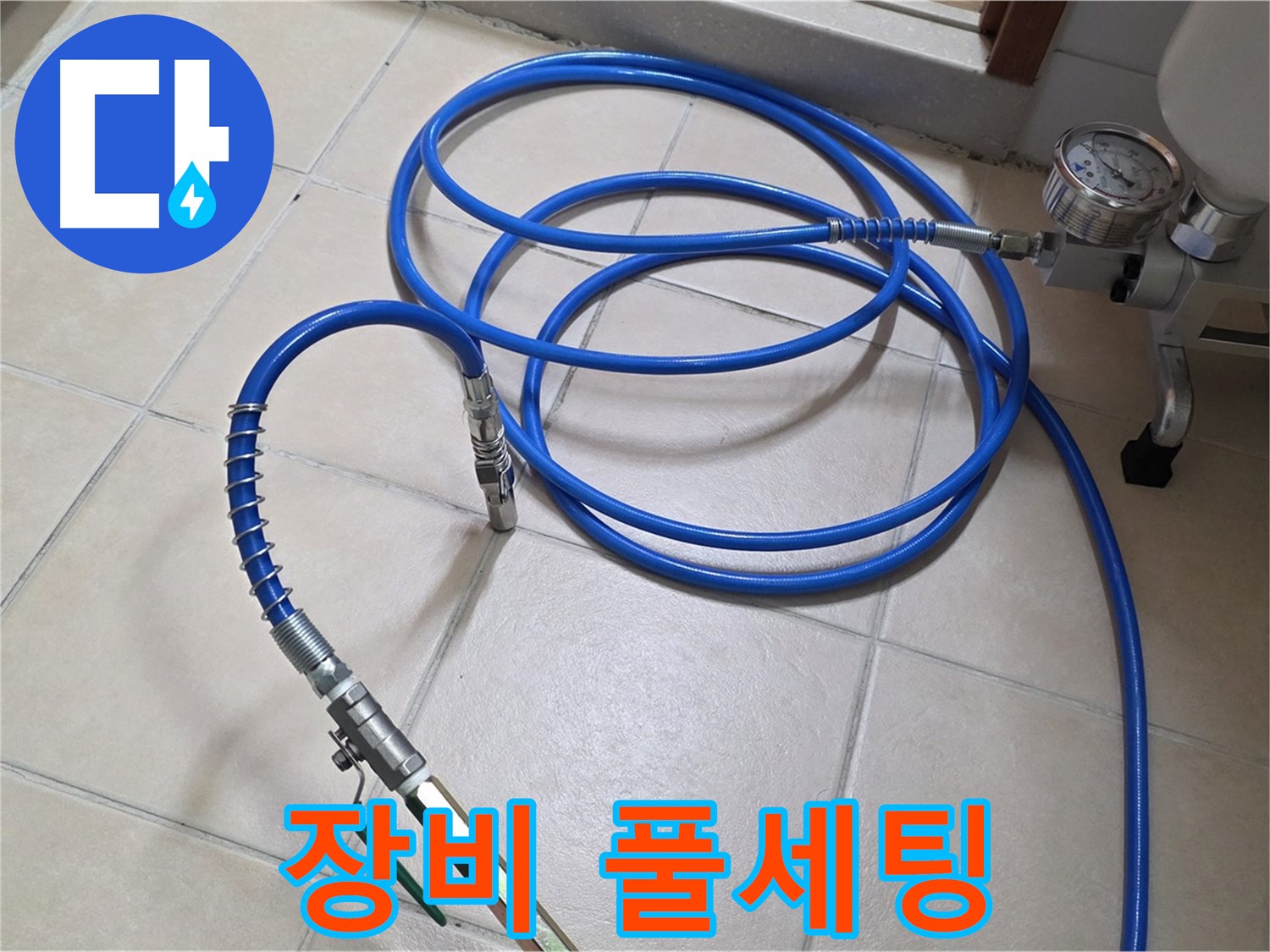 바닥 타일 위에 놓인 압력 게이지와 파란색 배관 호스입니다.