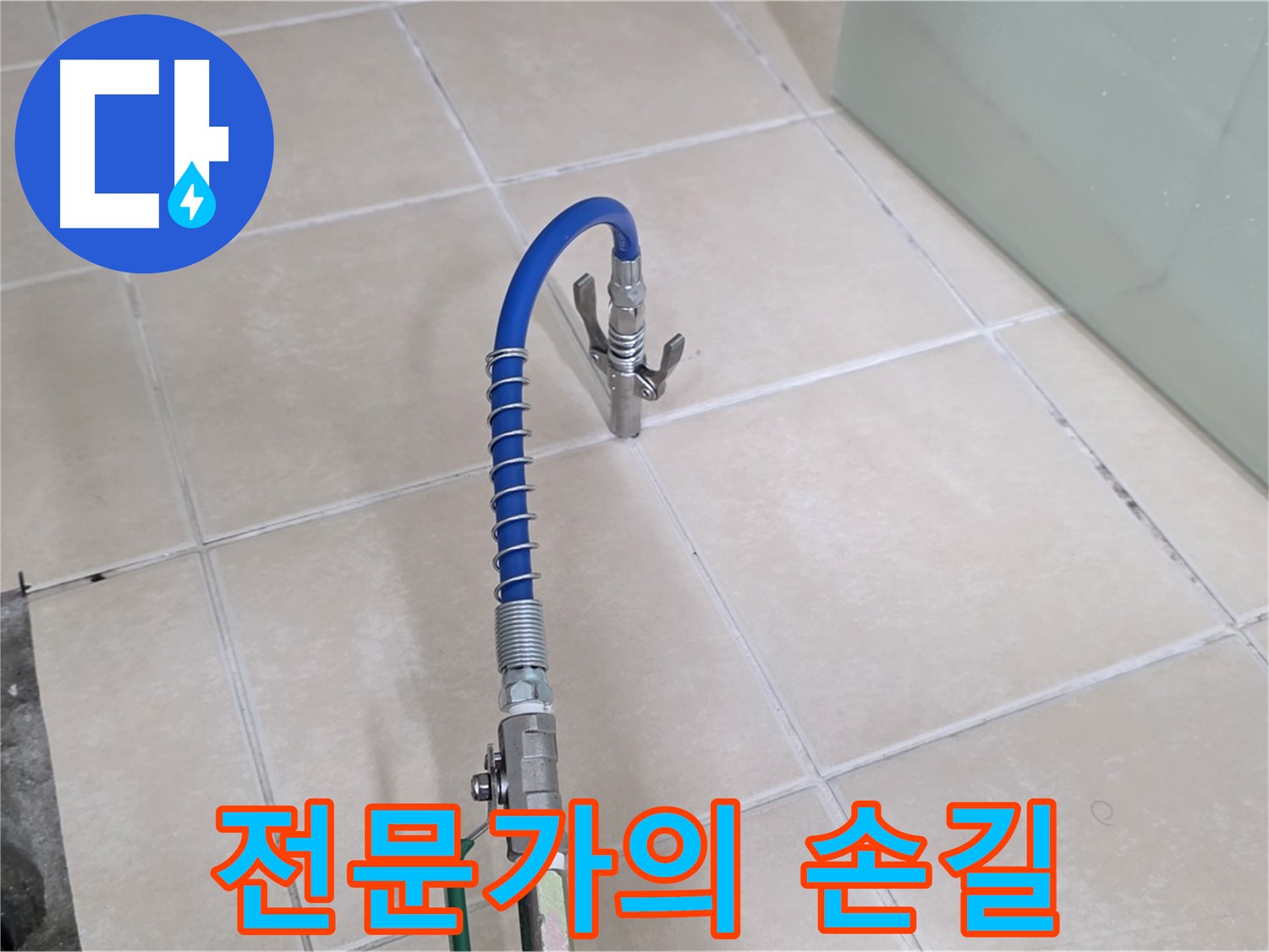 화장실 타일 바닥에 설치된 파란색 점검용 호스와 금속 부속품