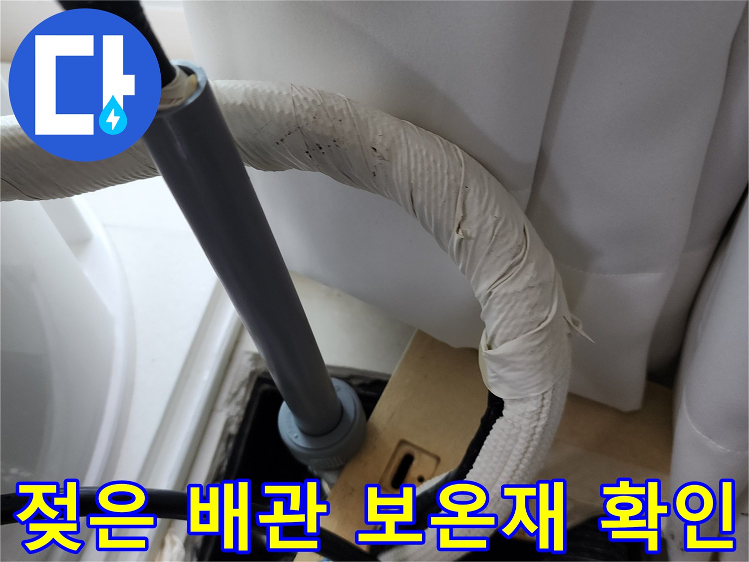 습기를 머금어 변색된 배관 보온재와 연결 부속의 근접 촬영입니다.