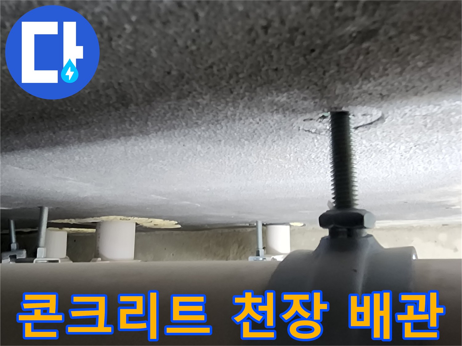 천장에 고정된 금속제 배관 부품과 거친 콘크리트 표면