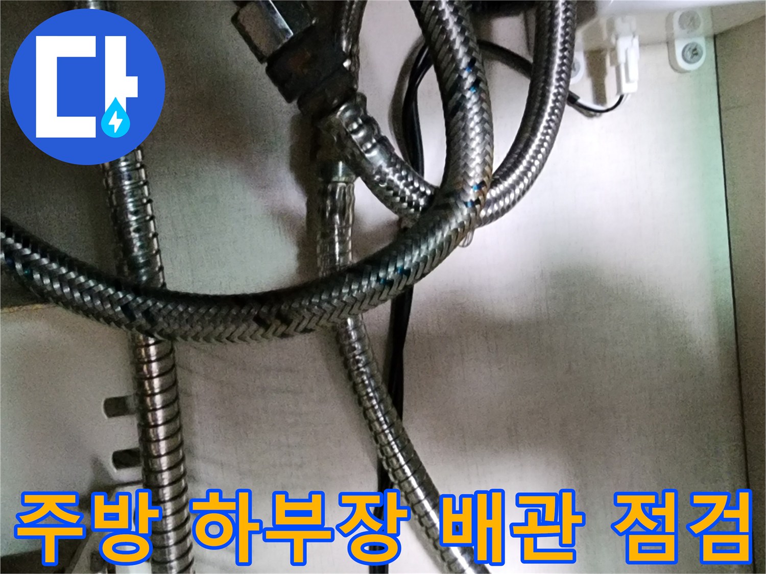 싱크대-하부의-금속재질-배관과-전기선이-함께-있는-모습