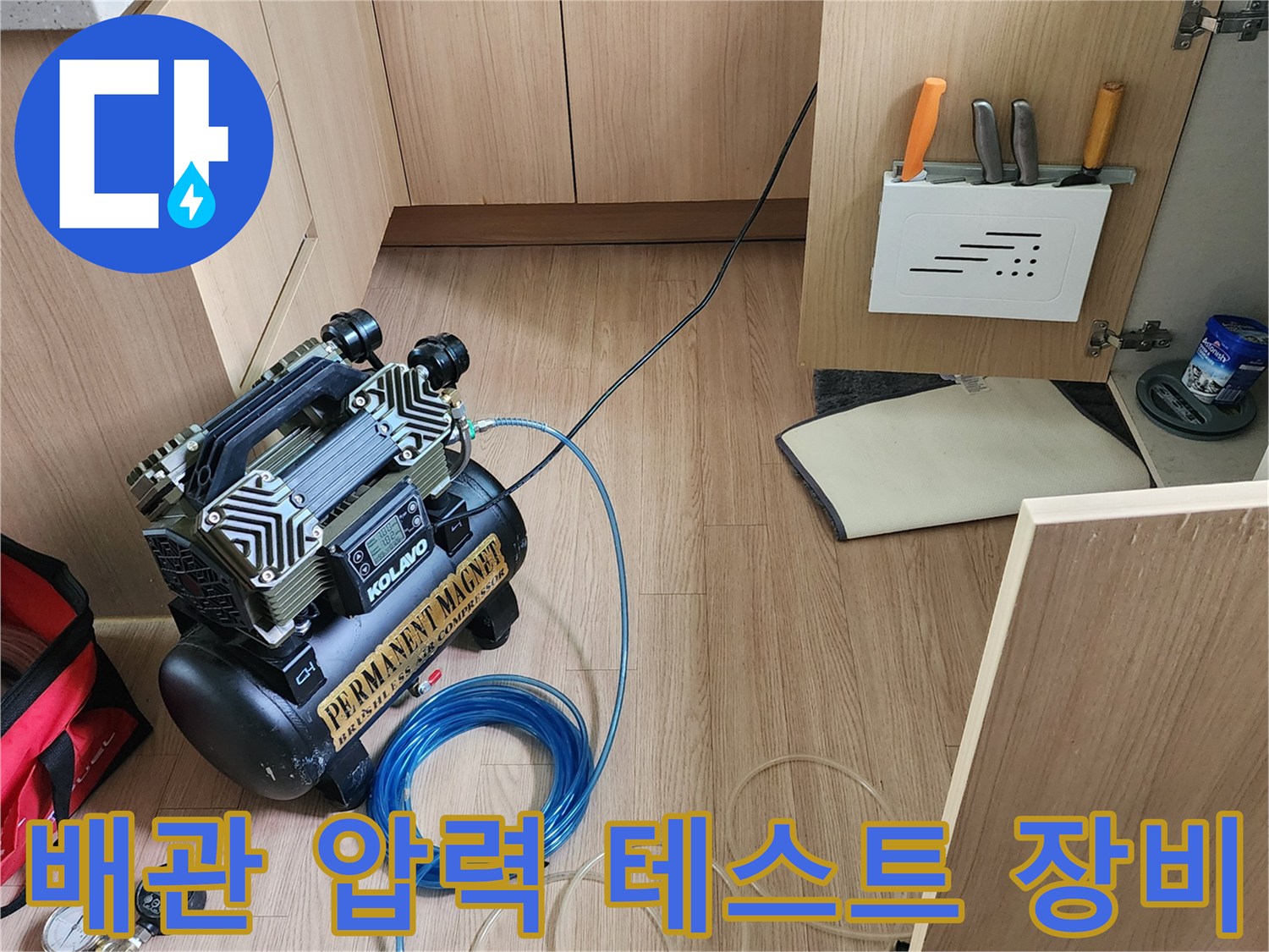 싱크대 하부장 바닥에 설치된 공기압 테스트용 컴프레서와 호스