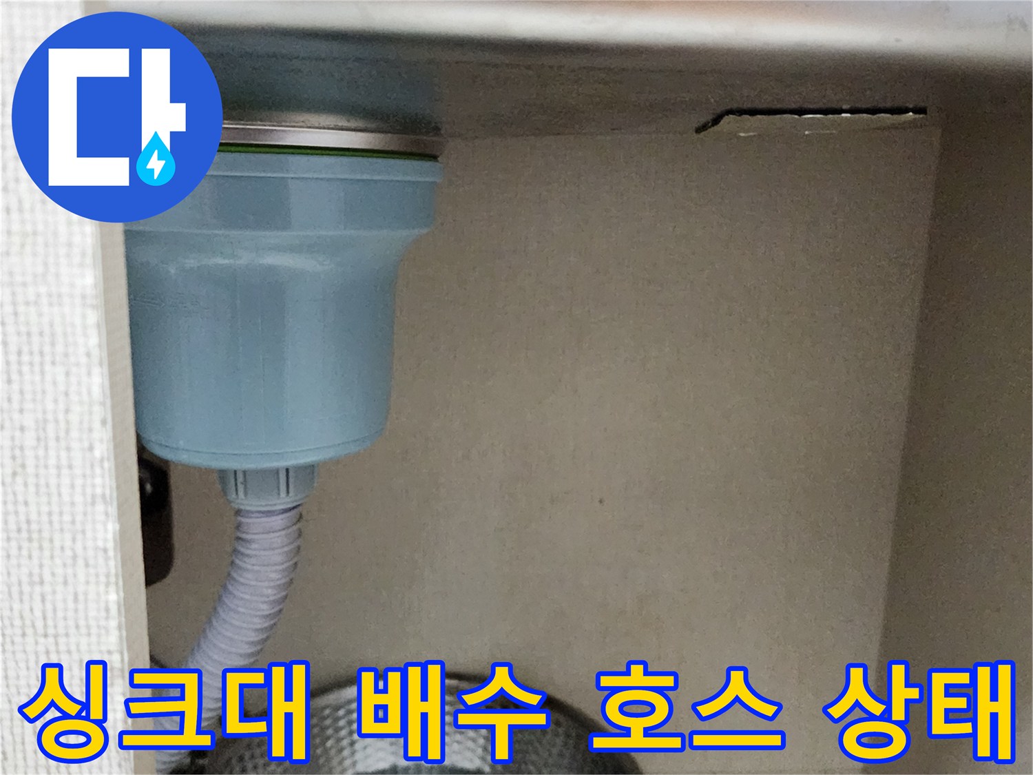 주방 싱크대 하부의 배수 호스와 배관 연결 부위 모습입니다.