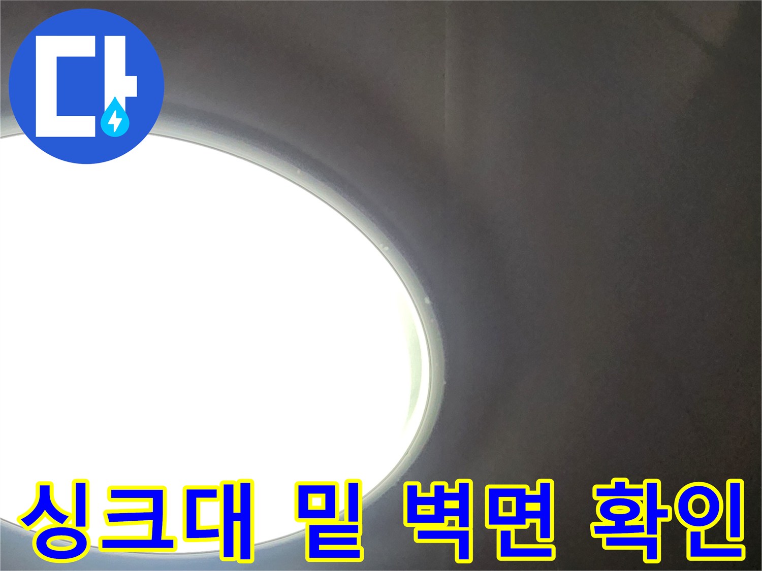 어두운 싱크대 하부 공간-벽 사이 틈새를 통해 내부를 들여다보는 모습입니다.