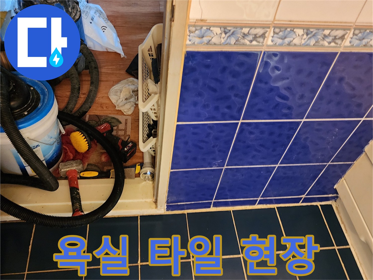 파란색 욕실 타일과 작업용 석션기 장비가 놓여 있는 모습