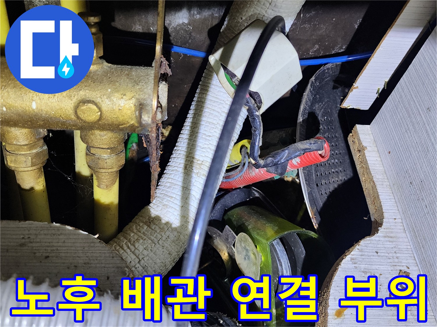 금속 급수관과 흰색 주름 호스가 겹쳐진 싱크대 하부 모습