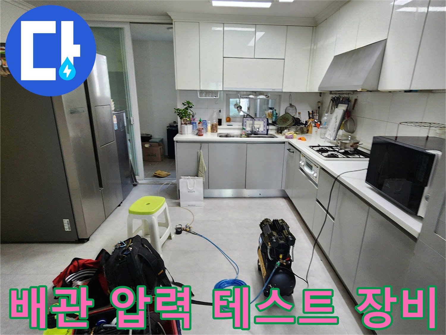 싱크대 아래 배수관 누수를 확인하기 위해 준비된 공기 압축기와 에어 호스