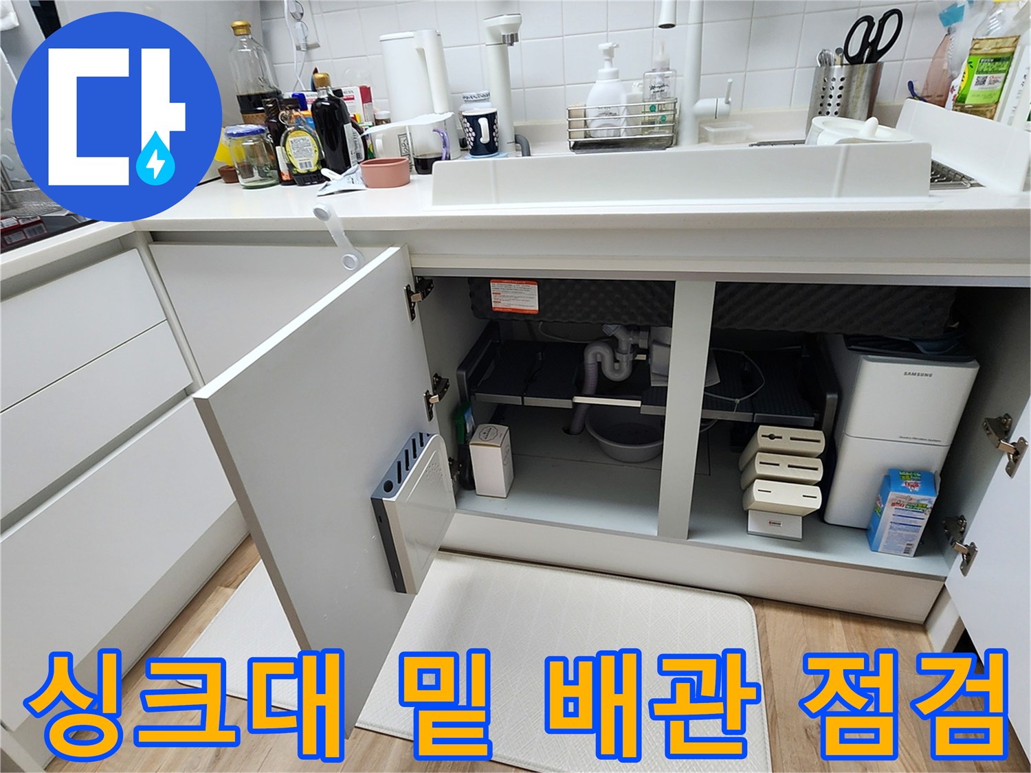 싱크대 하부장 안쪽의 배관과 주변 환경을 촬영한 사진입니다.