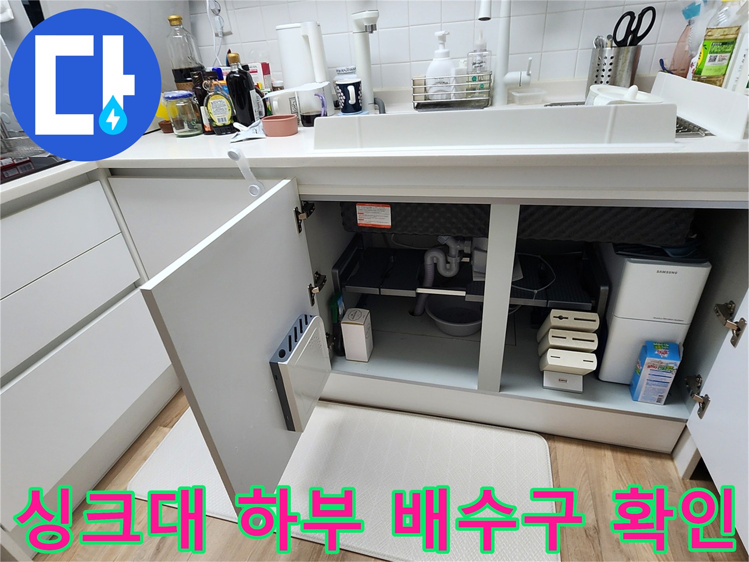 열려 있는 싱크대 하부장 내부의 배수 호스와 주변 공간 사진