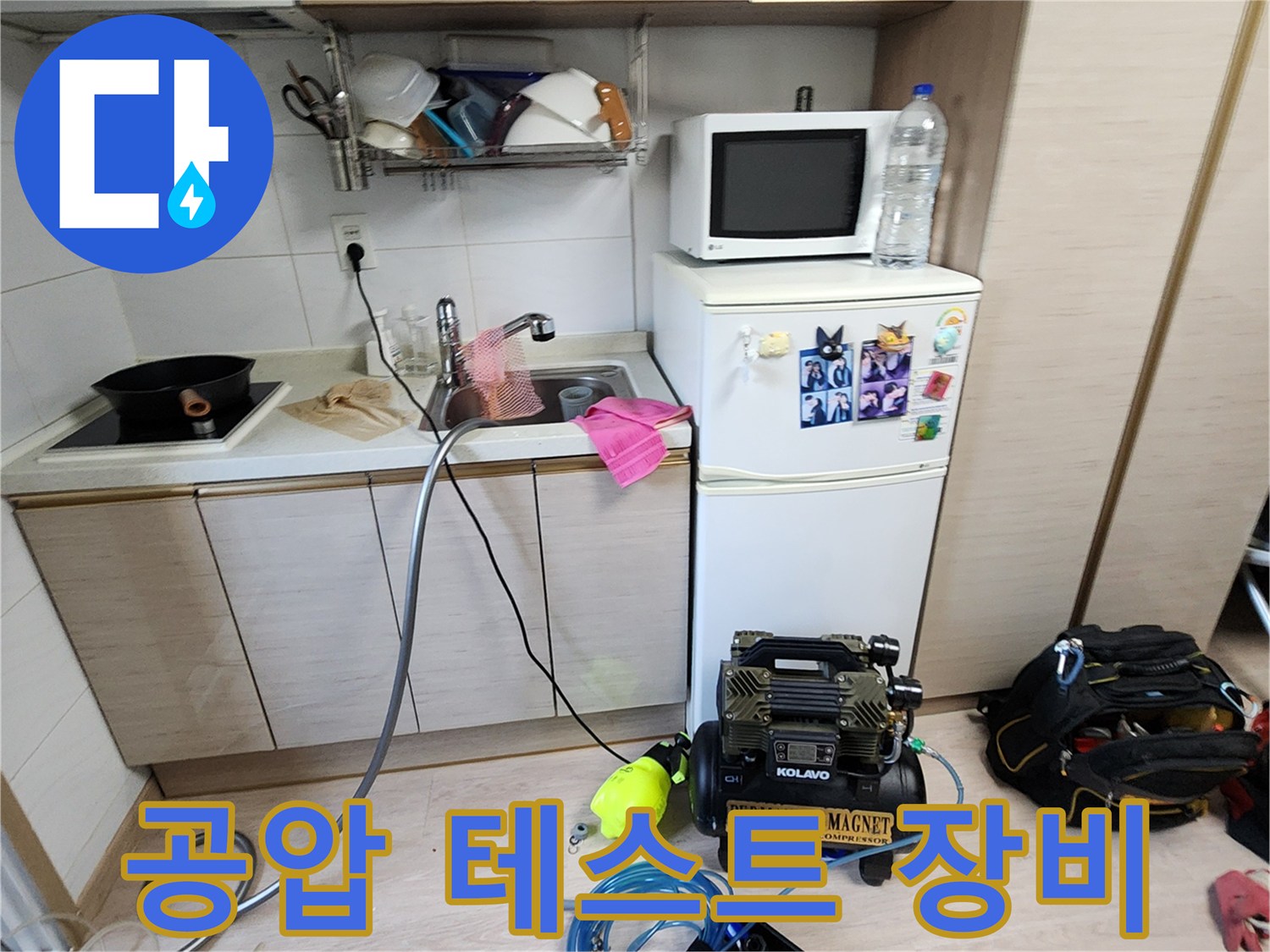 싱크대 하부장에 배치된 배관 압력 측정용 콤프레샤와 호스 연결 모습