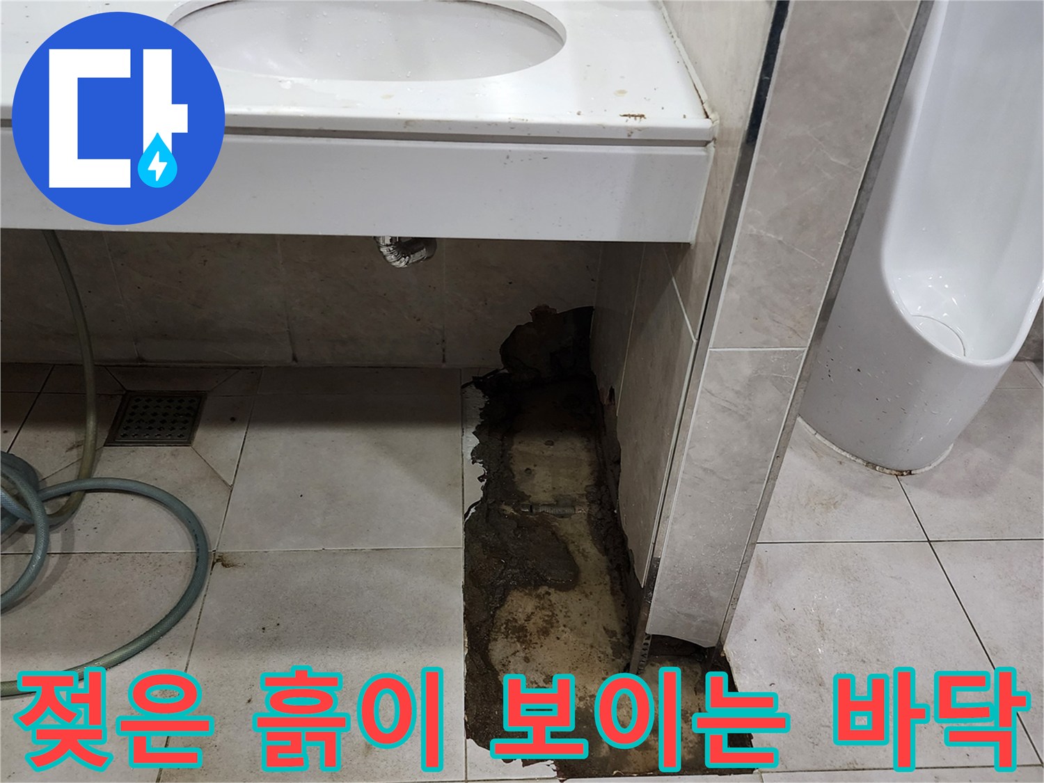타일을 깨내고 드러난 배관 주변의 젖은 토사 상태를 보여줍니다.