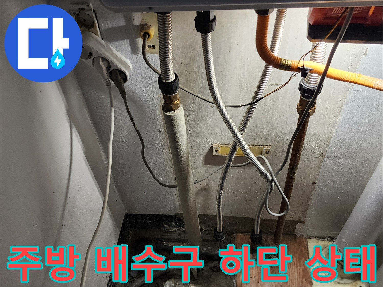 주방 싱크대 아래쪽의 복잡한 배수관 연결 구조물 사진