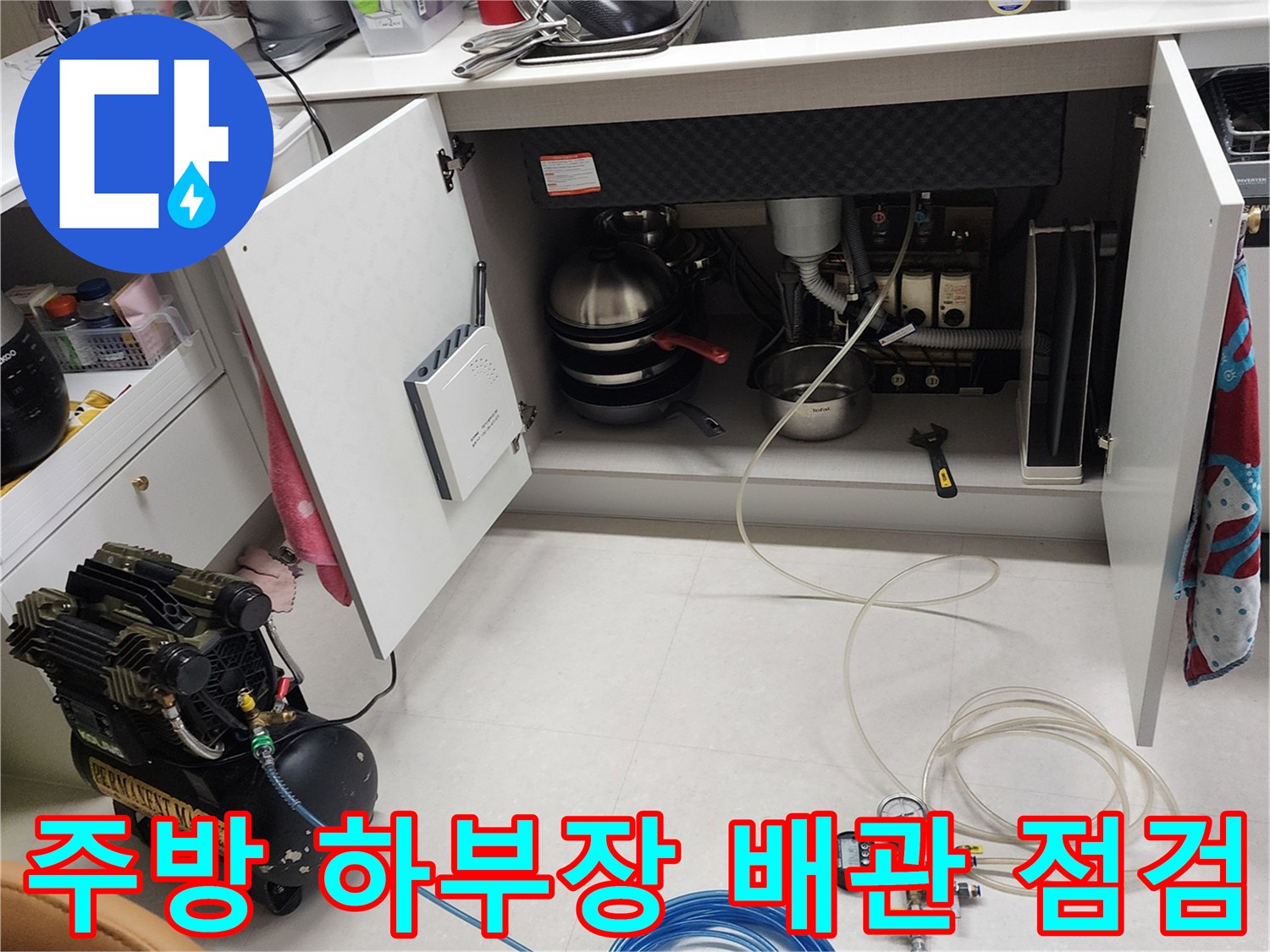 주방 싱크대 하부장 내부의 배관 상태를 확인하기 위해 공압 테스트 장비를 연결하여 정밀하게 진단하는 모습입니다.