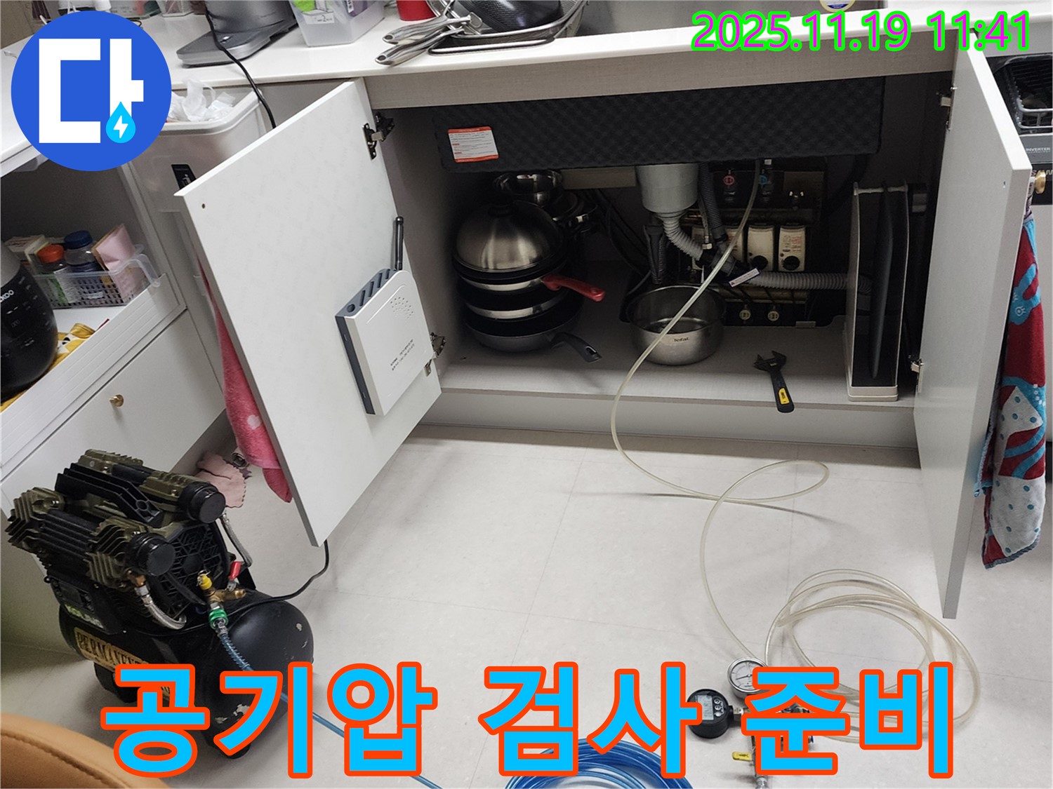 포천시 내촌면 마명리 누수 현장 - 싱크대 하부에서 공기압 검사를 준비하는 모습입니다. 장비들을 꼼꼼하게 살펴보고 있습니다.