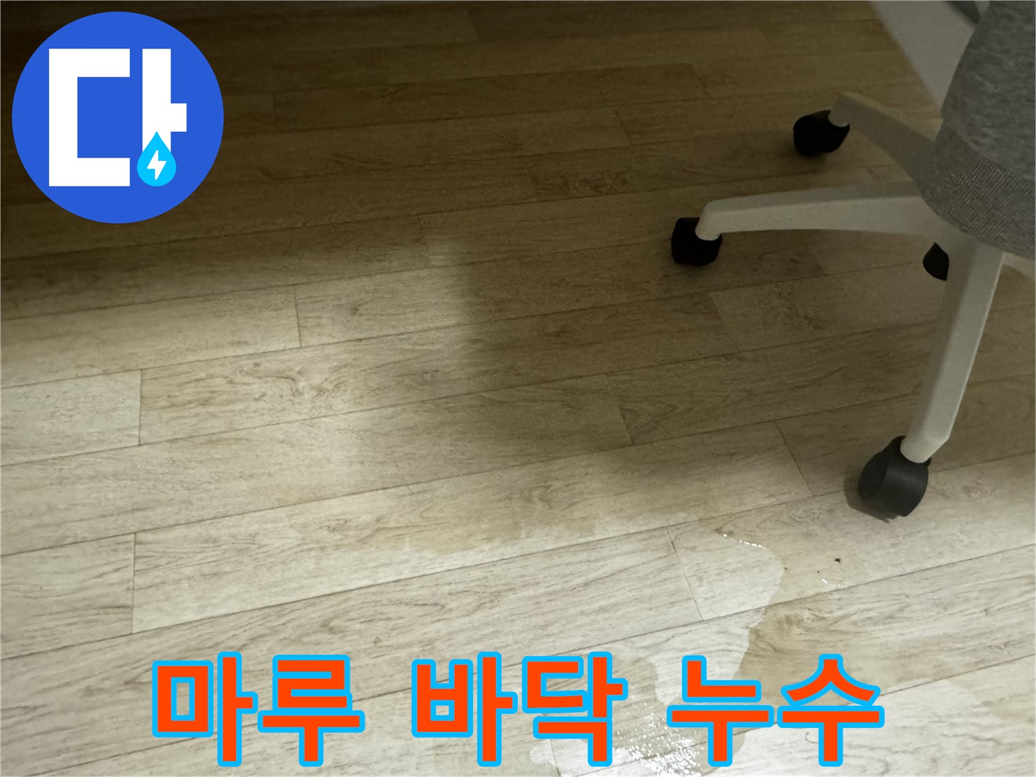 마루 바닥에 누수가 발생하여 물이 스며든 모습 - 변색과 얼룩이 보입니다.