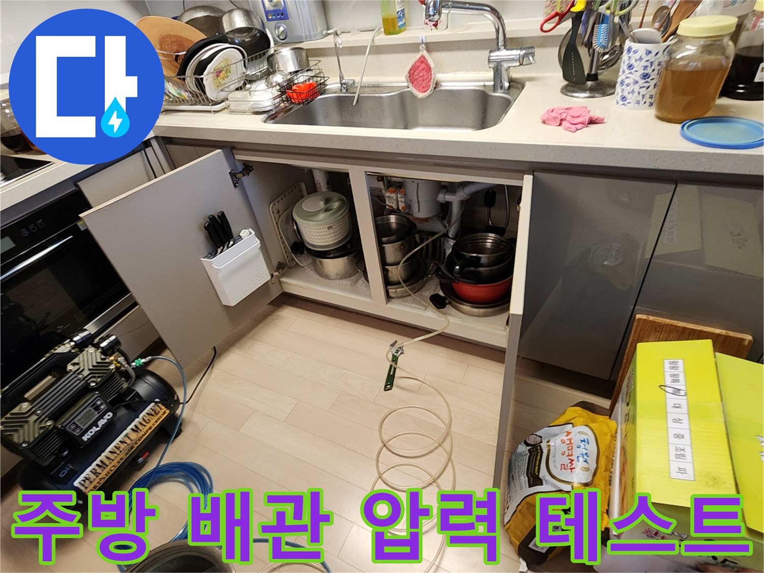 싱크대 하부장 내부 배관과 공기압 테스트용 컴프레셔 연결 상태