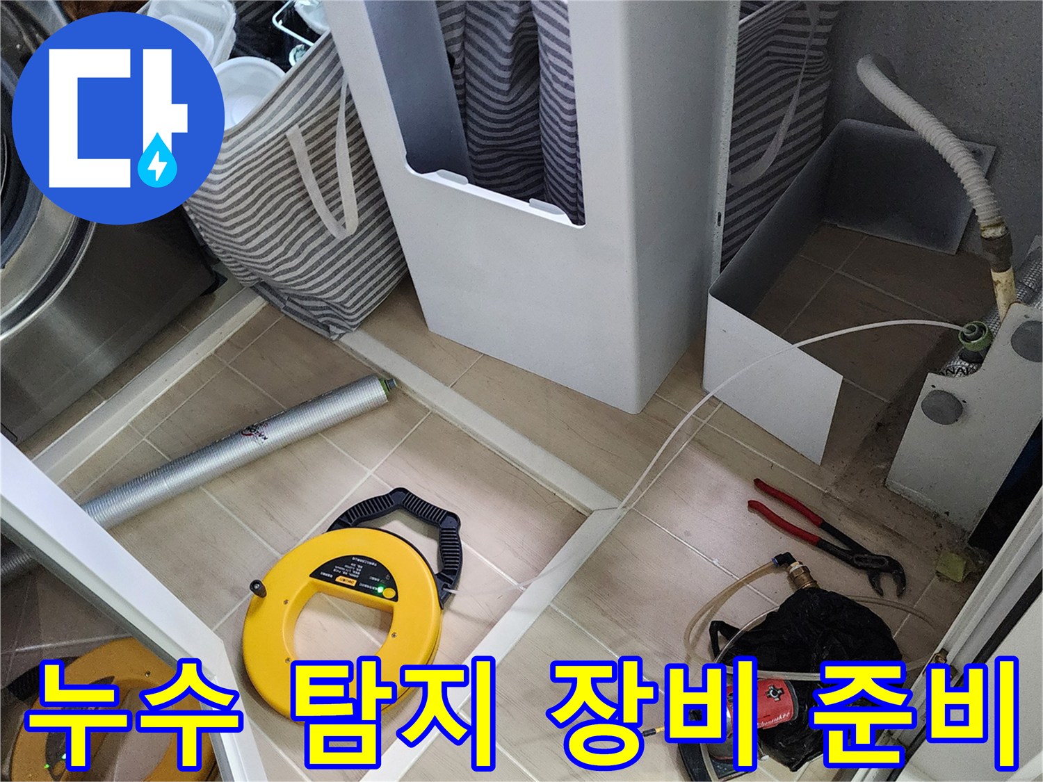바닥에 배치된 노란색 가스 릴과 작업용 전동 드릴 및 공구