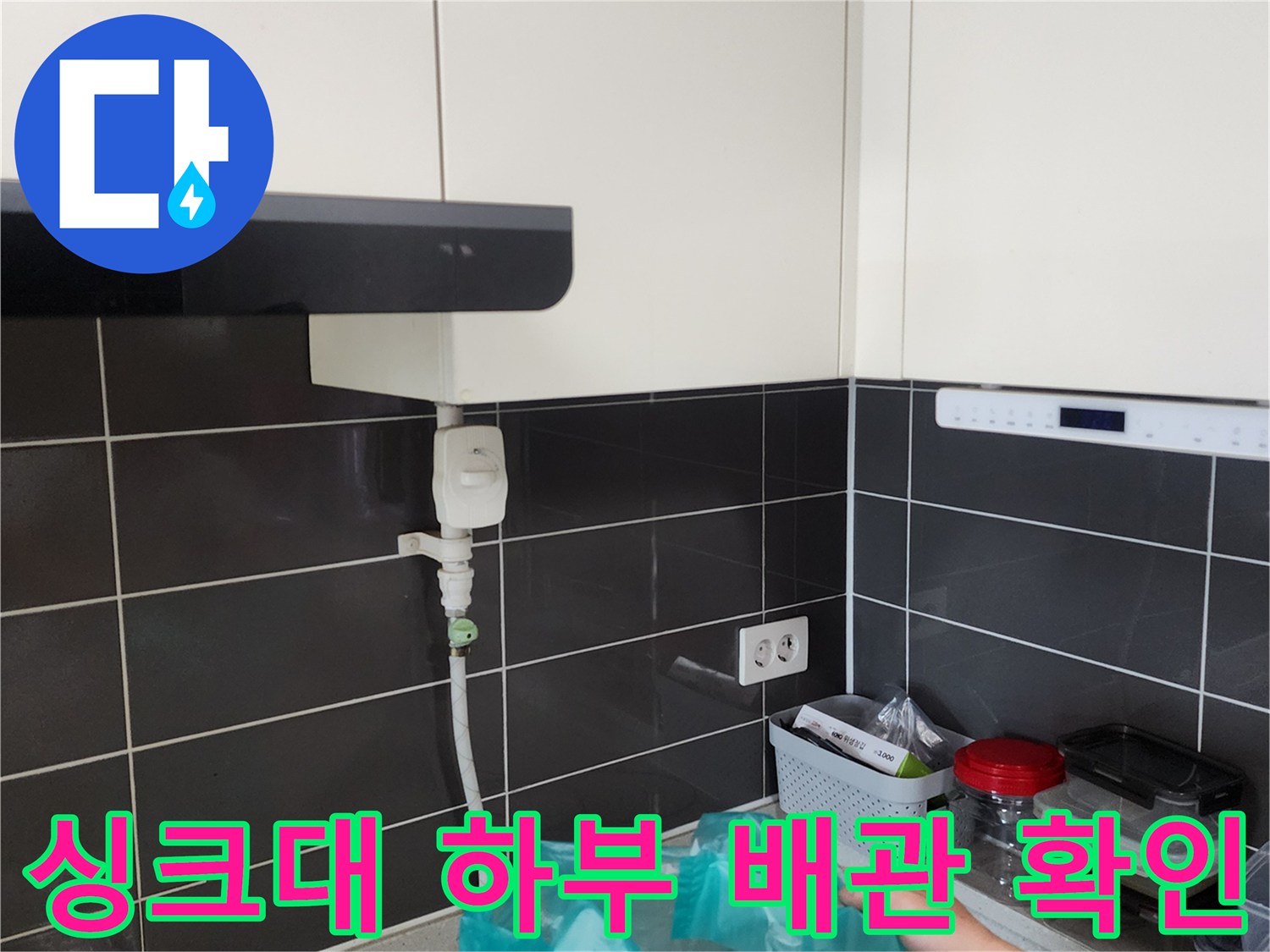 주방 싱크대 아래쪽 배관 연결부와 벽 타일 근접 촬영