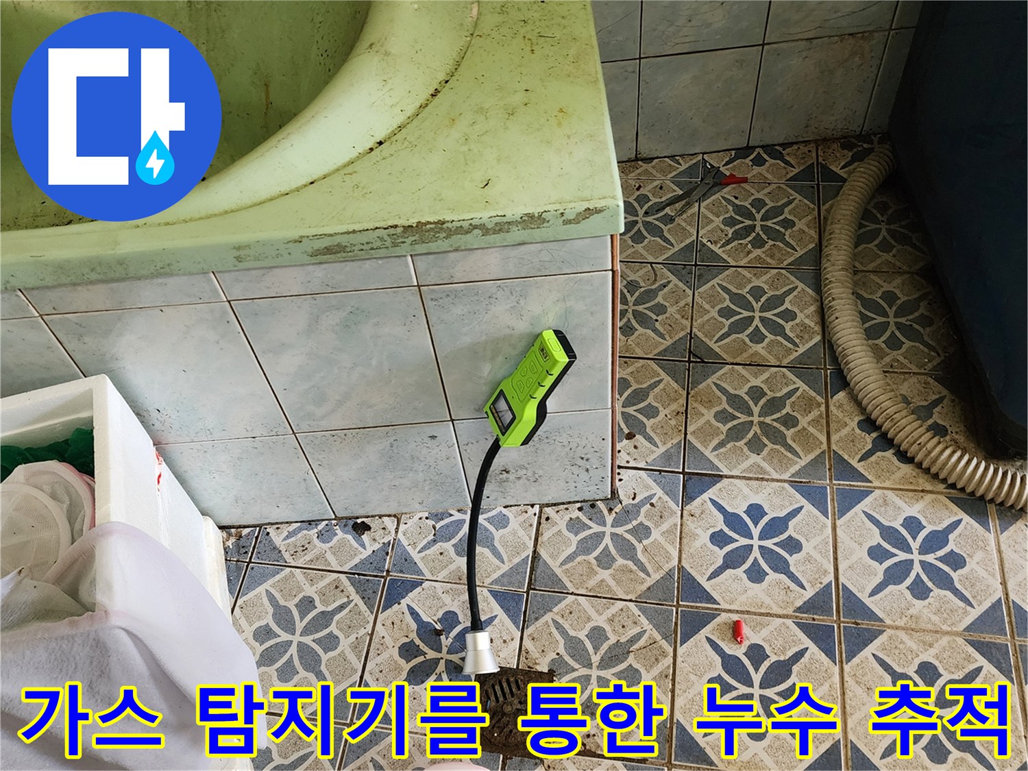 욕실 바닥 타일 위에서 초록색 가스 탐지기로 배관의 누수 반응을 정밀하게 살피는 장면입니다.