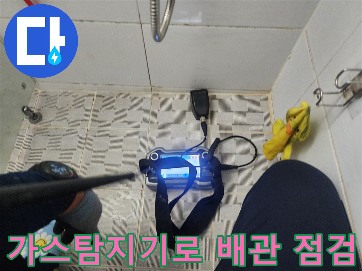 욕실 바닥 타일 위에서-가스 탐지기를 사용하여-배관 내부의 누수 지점을 찾는 모습