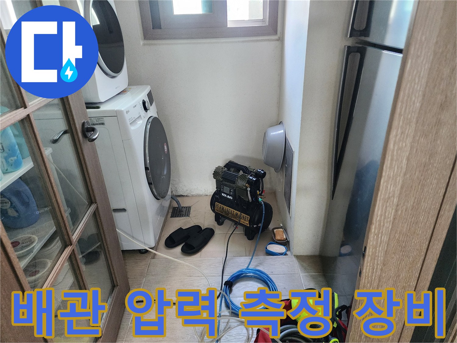 세탁실 구석에 배치된 검은색 콤프레셔와 파란색 점검 호스