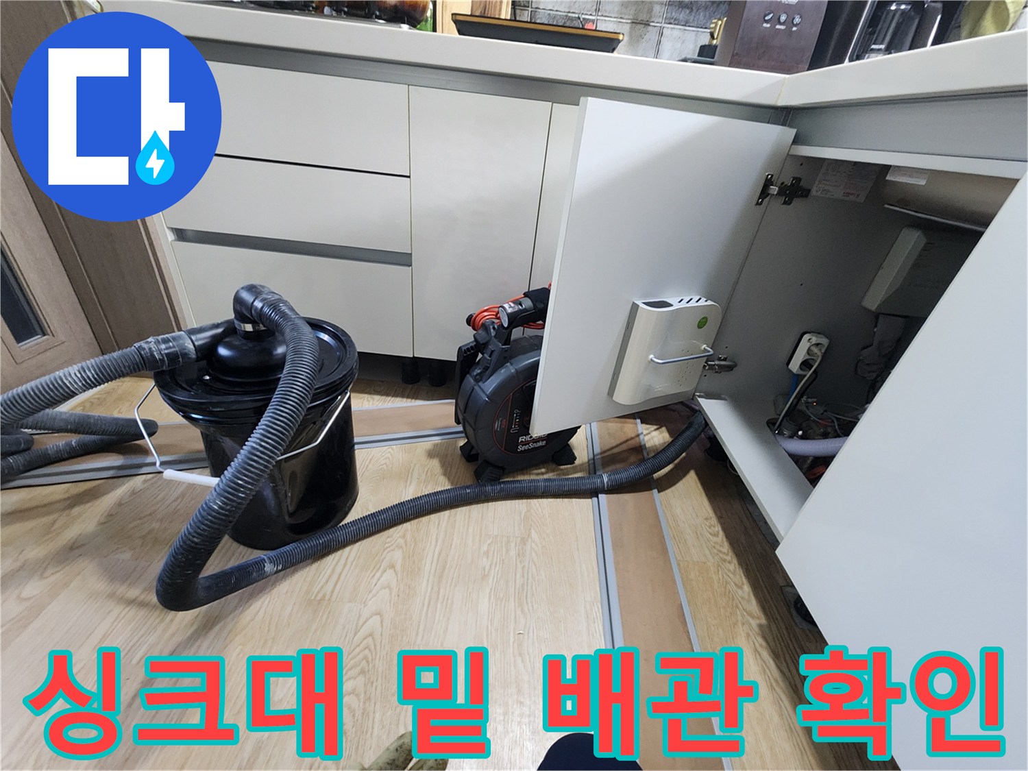 주방 싱크대 하단 공간의 배관 연결 상태를 점검하는 현장 사진