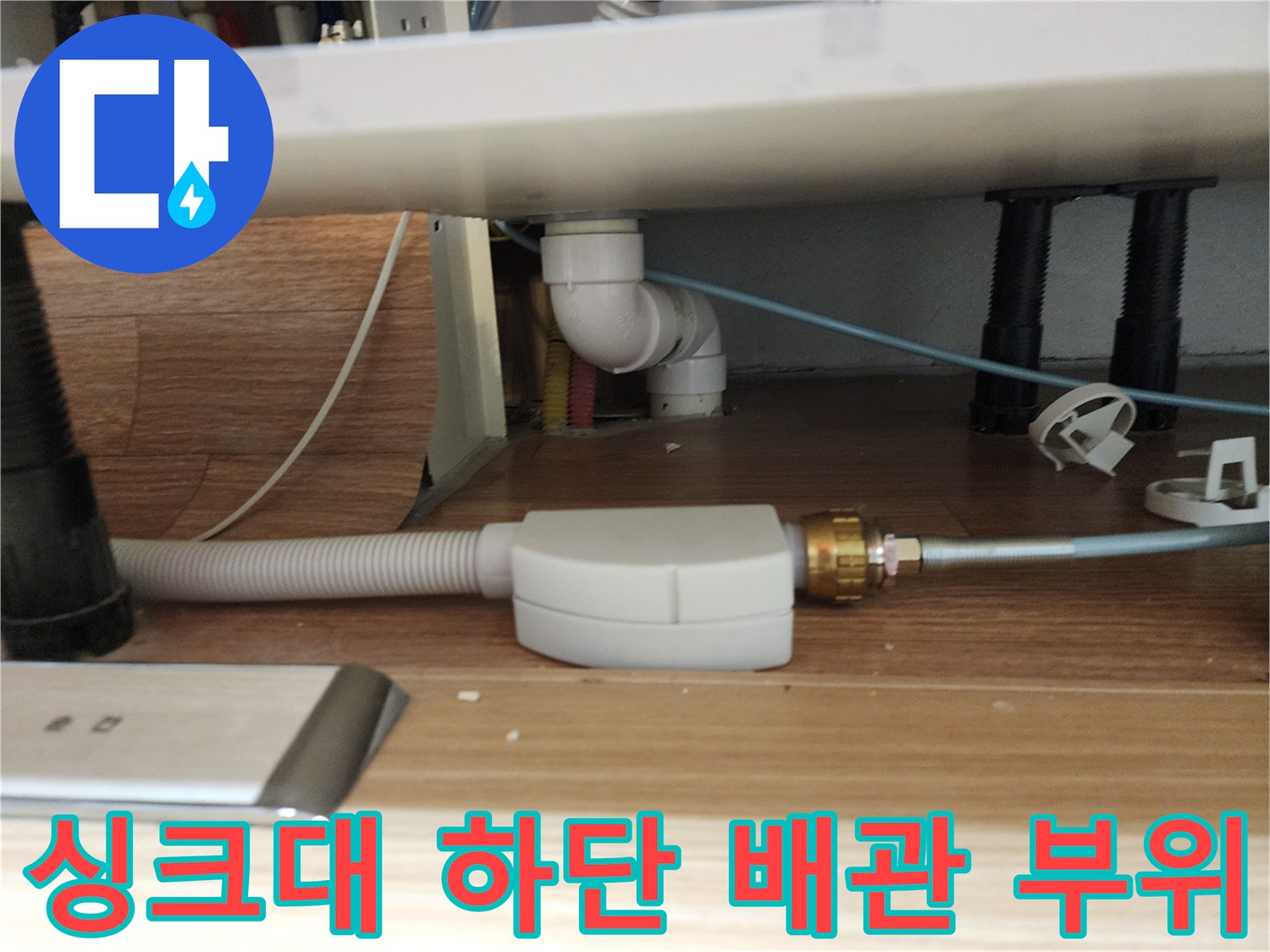 주방 싱크대 아래쪽의 하얀색 배관과 회색 호스 연결 상태