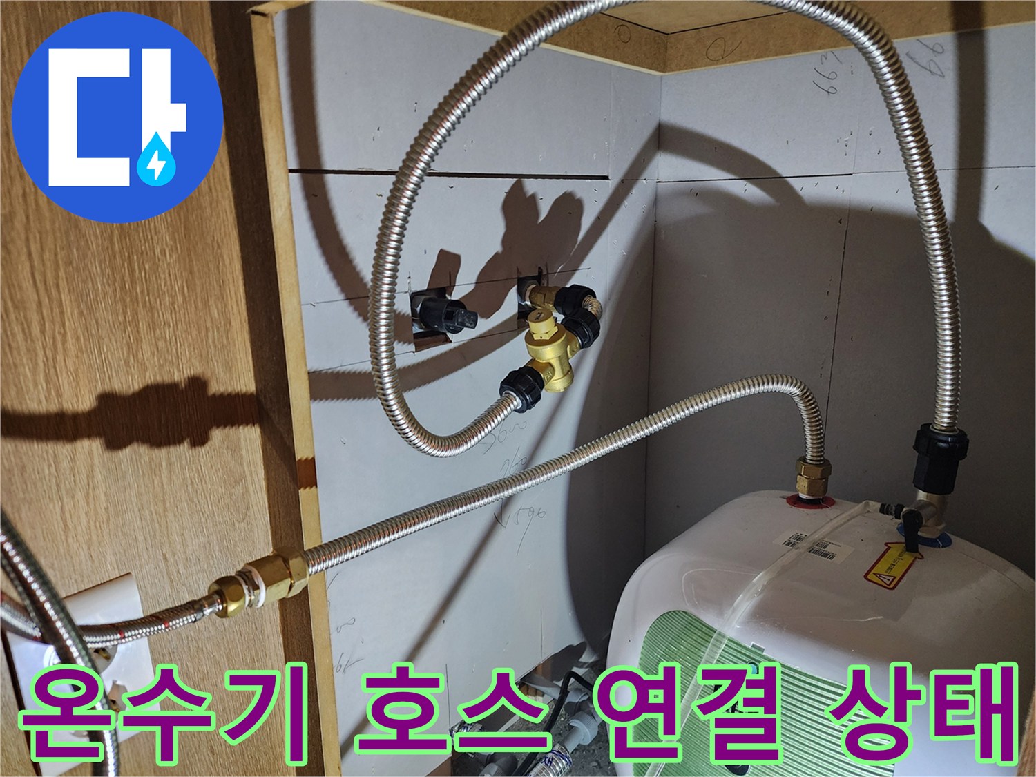 전기 온수기에 연결된 은색 금속 호스의 상세 사진