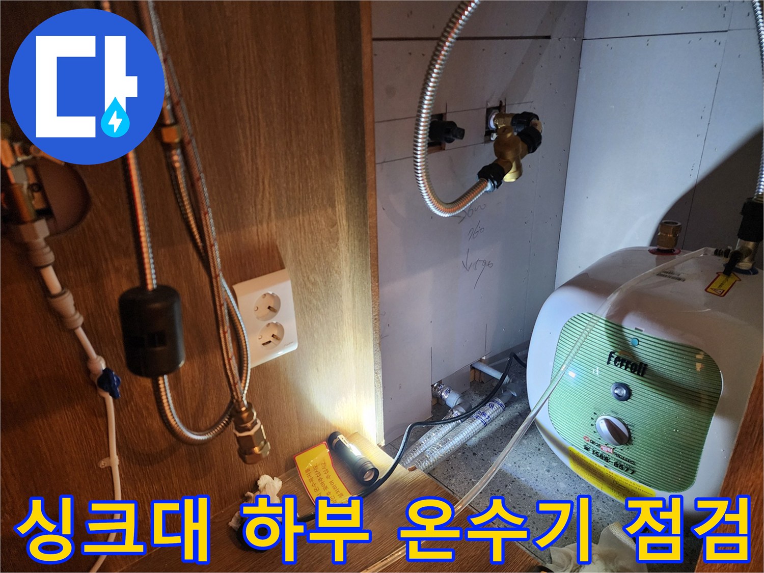 주방 싱크대 아래 설치된 전기 온수기와 수도 연결 부위