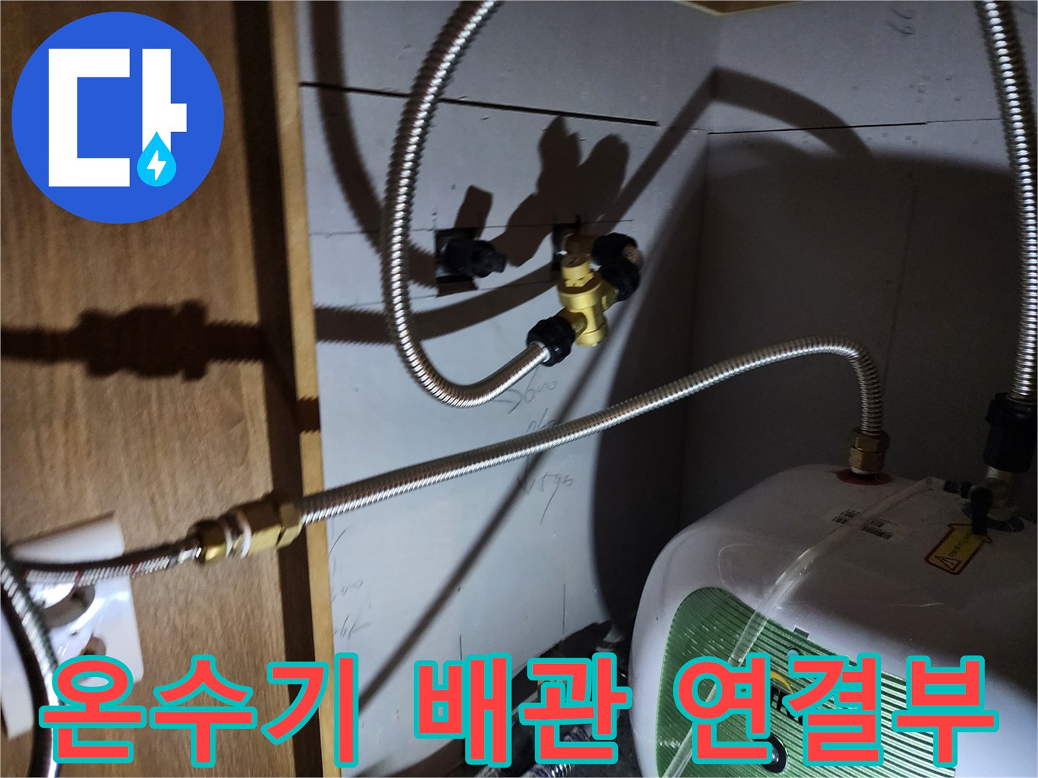 주방 싱크대 하부장 내 설치된 전기 온수기와 금속 배관의 연결 상태