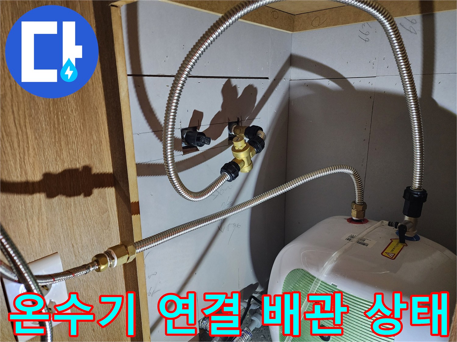 주방 하부장 내 설치된 전기 온수기와 플렉시블 호스 연결 부위 모습