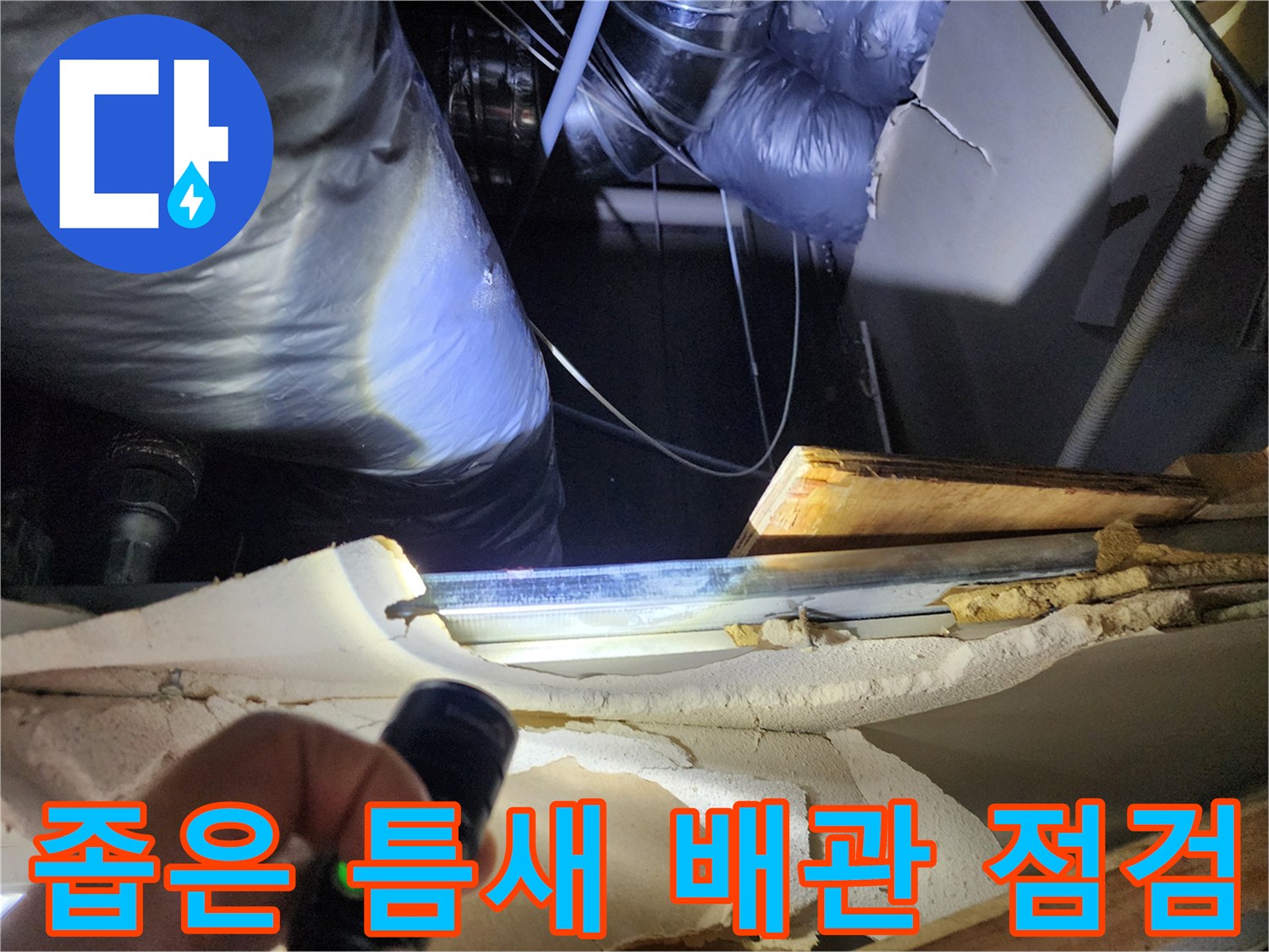 손전등 빛으로 비춰진 싱크대 하단부 배관 연결 부위의 습기 상태