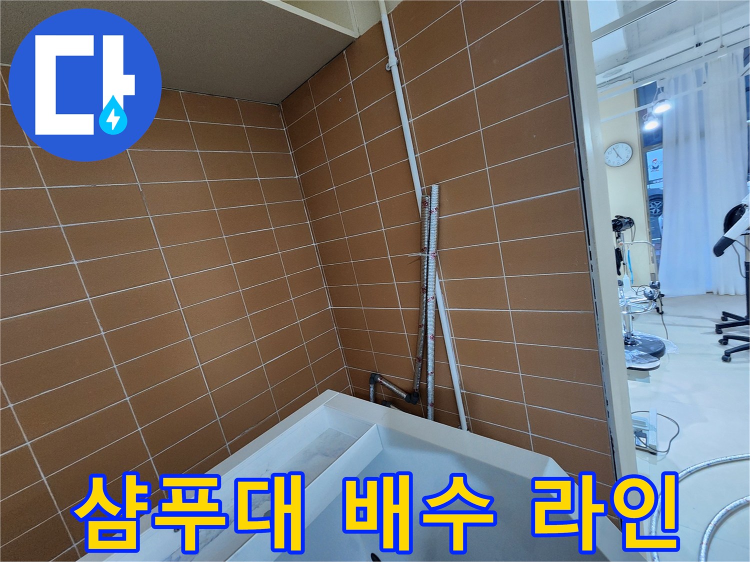 샴푸대와 연결된 타일 벽면의 하수 배관 설치 모습 - 보수 작업 준비 단계