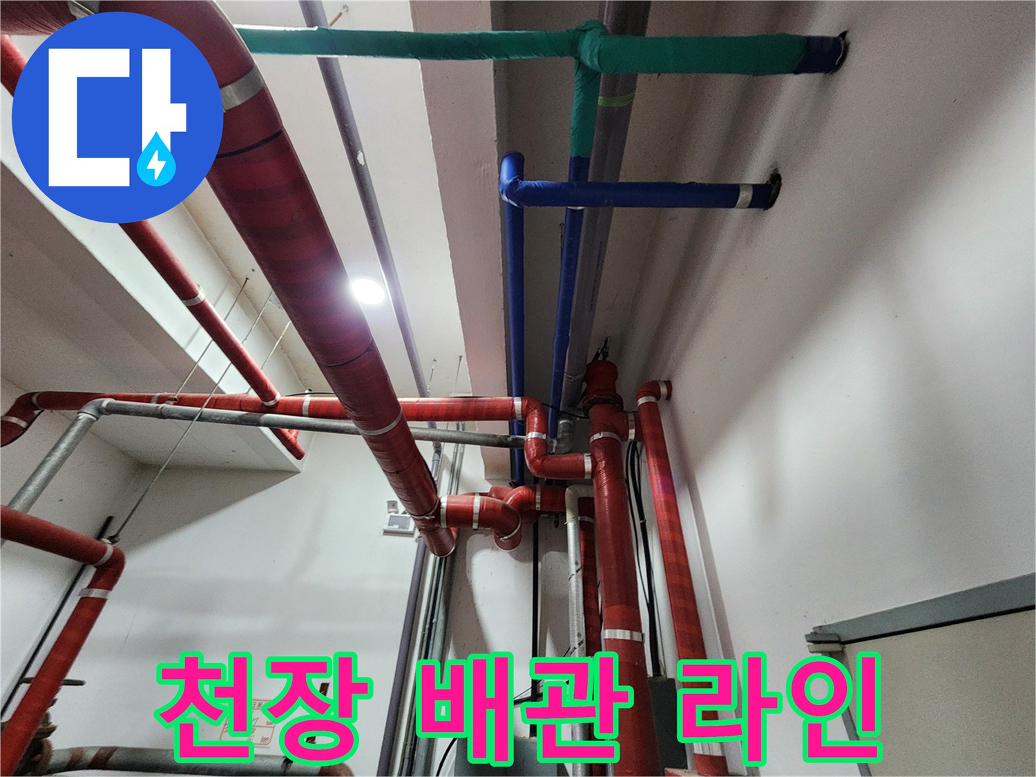 여러 색상의 배관이 천장에 고정되어 있는 배관 설비 사진입니다.
