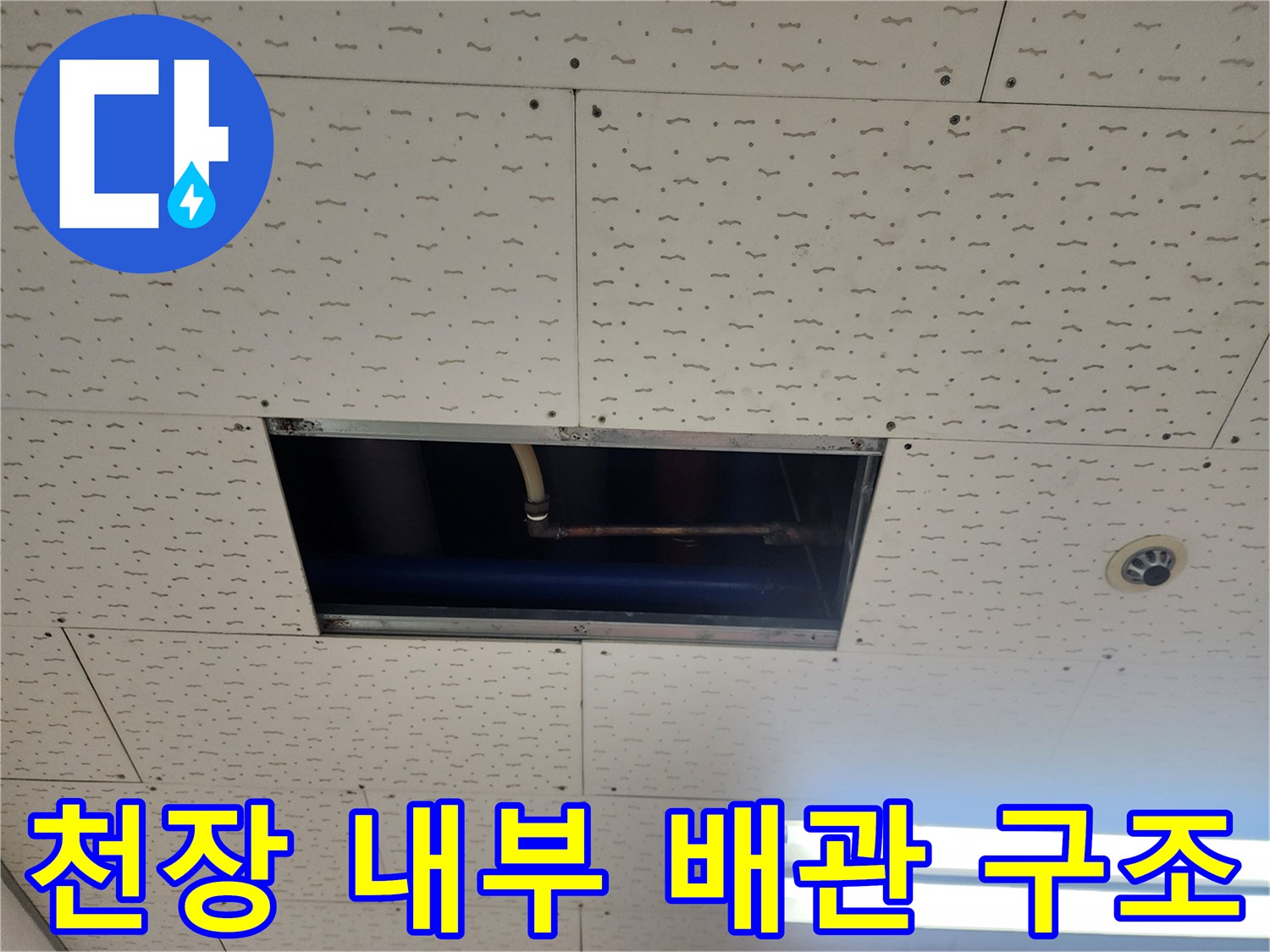 천장 점검구 내부의 노출된 배관과 천장 판넬의 모습입니다.