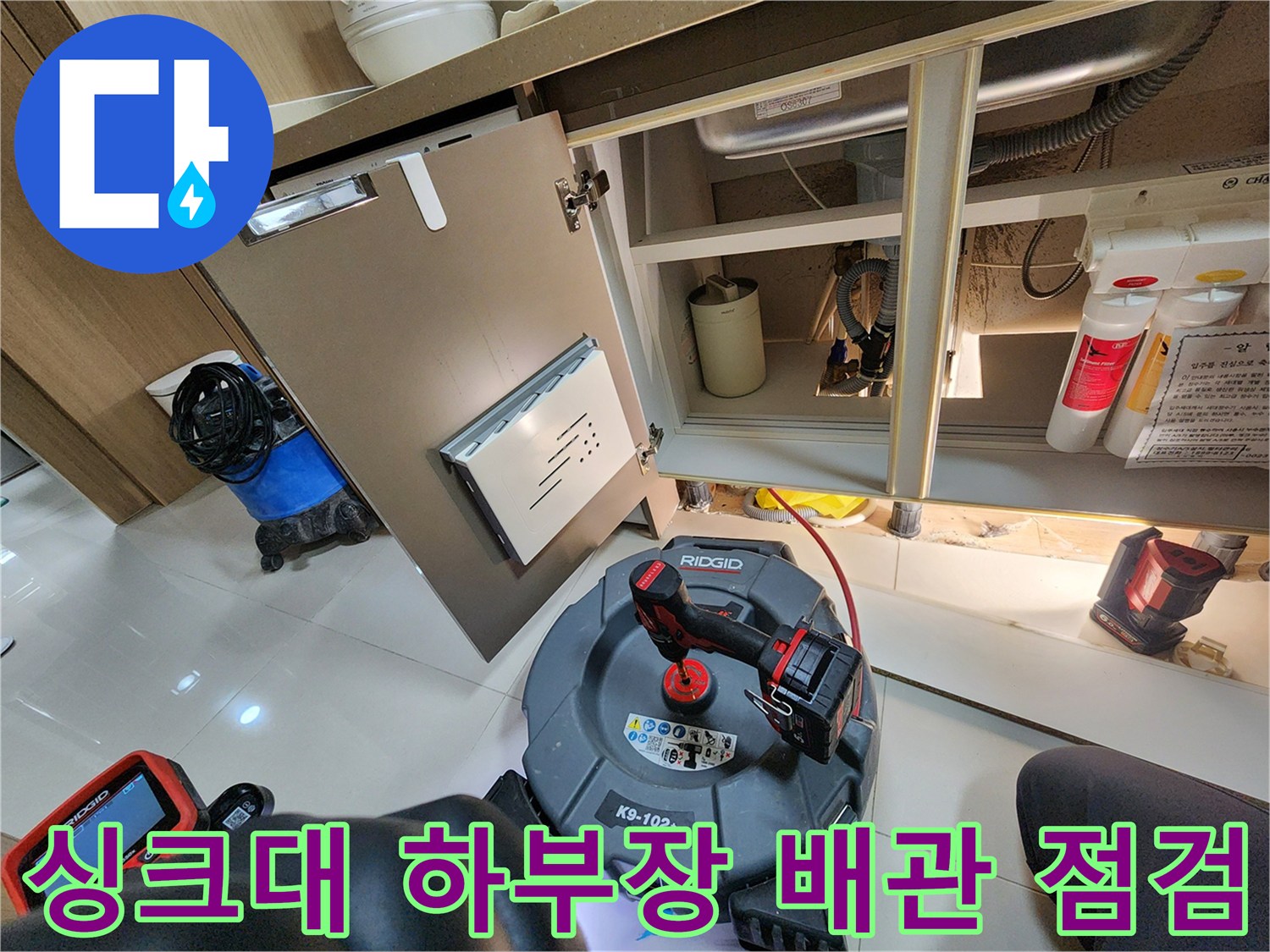 싱크대 하부장 내부의 복잡한 배수 구조와 장비를 확인하는 사진입니다.