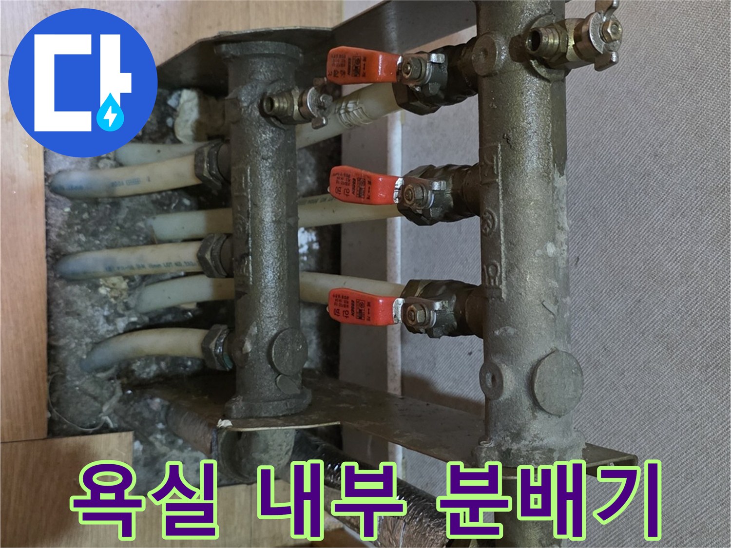 벽면에 설치된 금속 소재의 온수 분배기와 연결 배관 모습입니다.