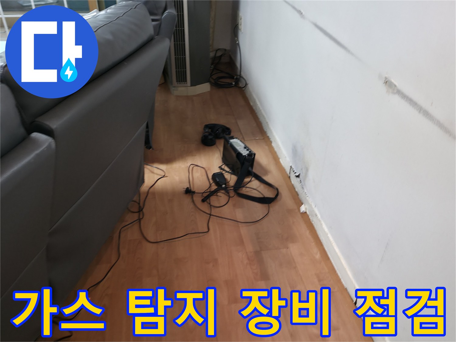 거실 소파 옆 벽면에서 배관 누수를 확인하기 위해 가스 탐지기를 설치한 모습입니다.