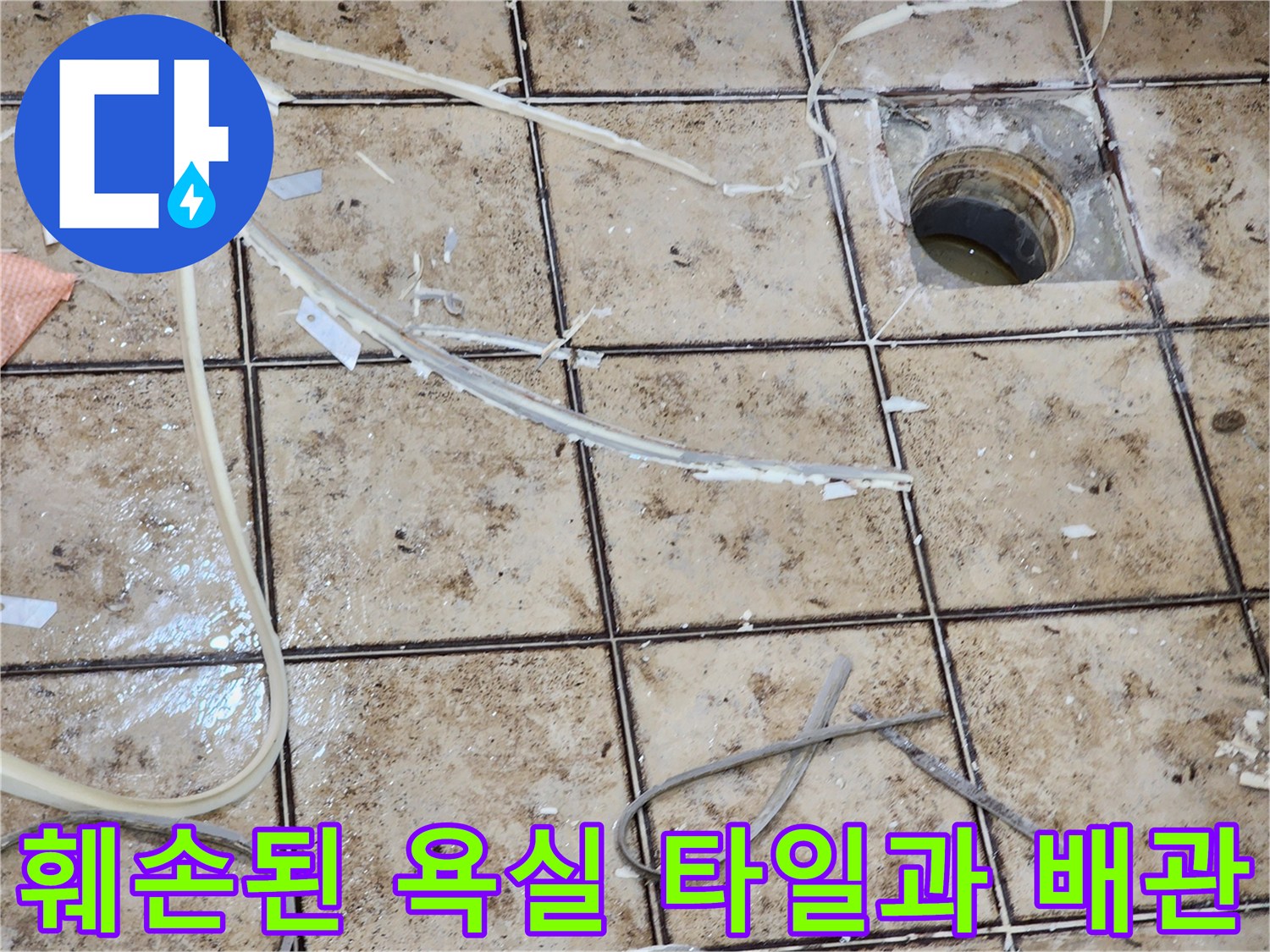배수구 주변의 훼손된 타일 조각과 노출된 배관 부위를 나타내는 이미지입니다.