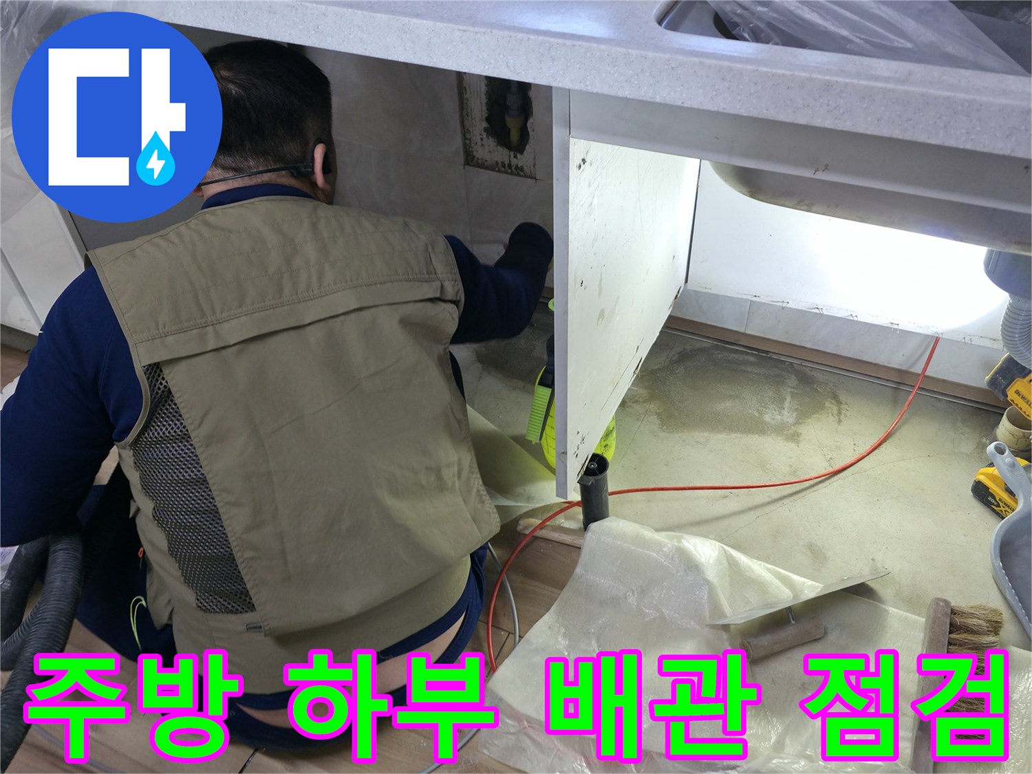 싱크대 아래쪽 구석진 곳의 배관 누수 여부를 확인하는 작업 장면입니다.