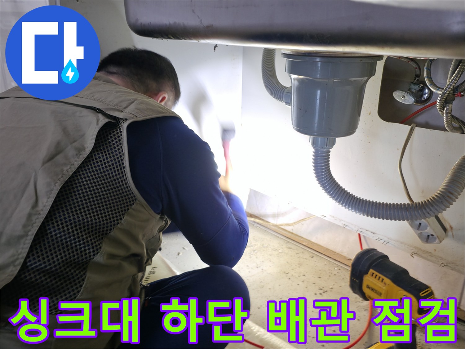 싱크대 아래쪽의 수도 부속과 배수 호스를 확인하는 작업자