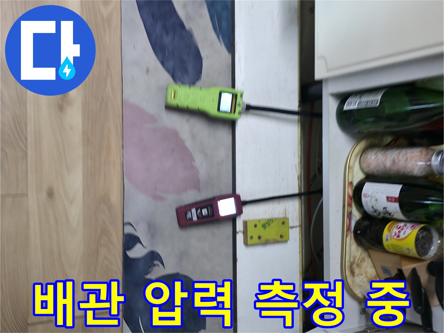 싱크대 하부 배관에 연결된 가스 탐지 장비와 압력계