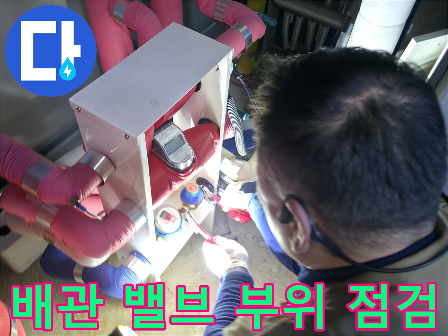 분홍색 보온재 배관과 금속 밸브 장치를 확인하는 엔지니어의 손길