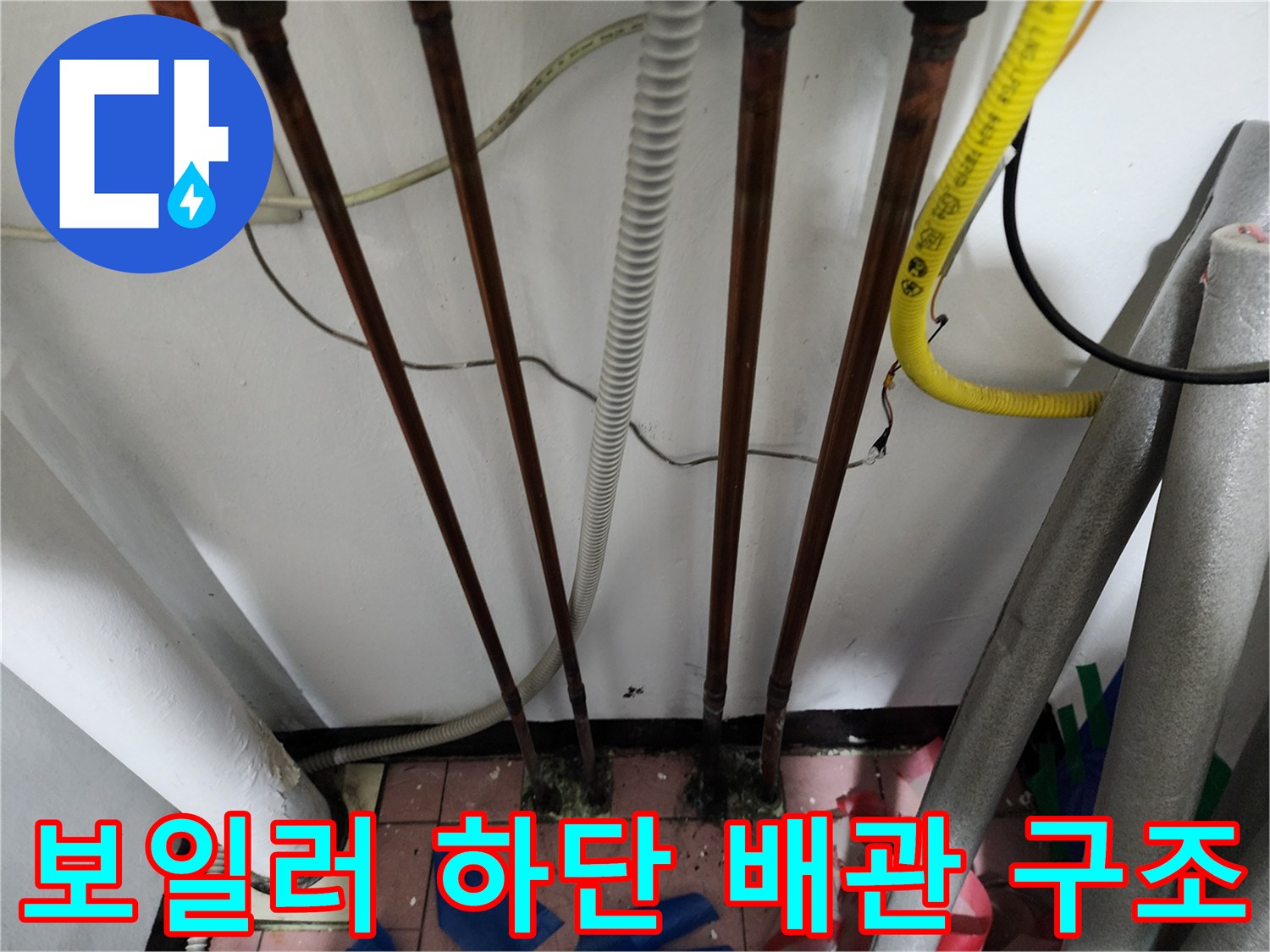 흰색 주름관과 동배관이 함께 설치된 보일러실 바닥 부근