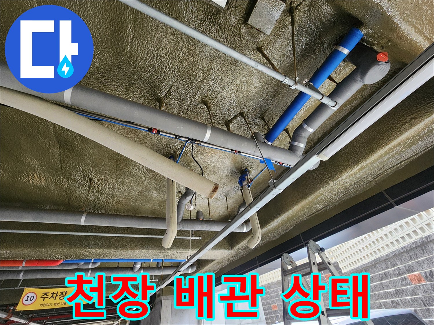 은색 배관과 파란색 보온재가 설치된 지하 주차장 천장 내부 모습