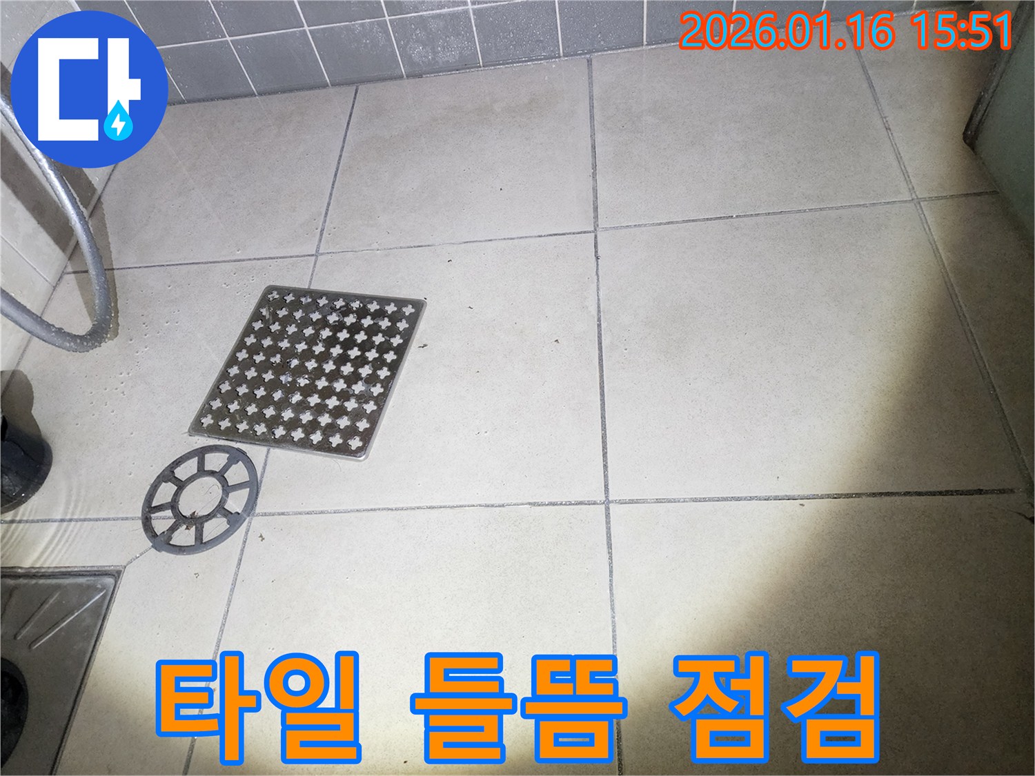 이 이미지는-욕실 배수구 커버를-제거한 후-주변 타일의-들뜸 현상을-확인하는-장면을 보여줍니다
