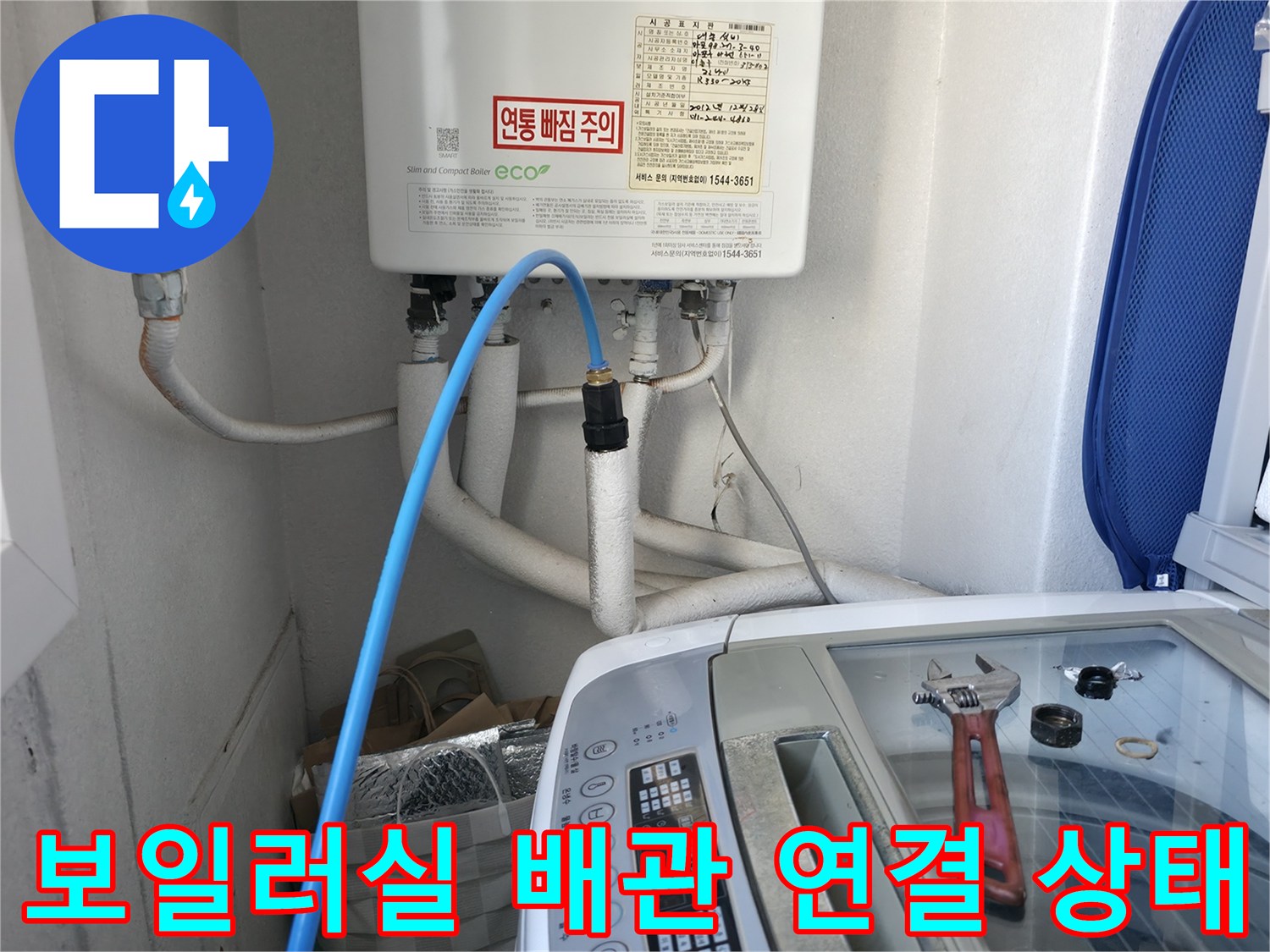 보일러실 내부의 파란색 급수 호스와 하얀색 배관 연결 부위 모습