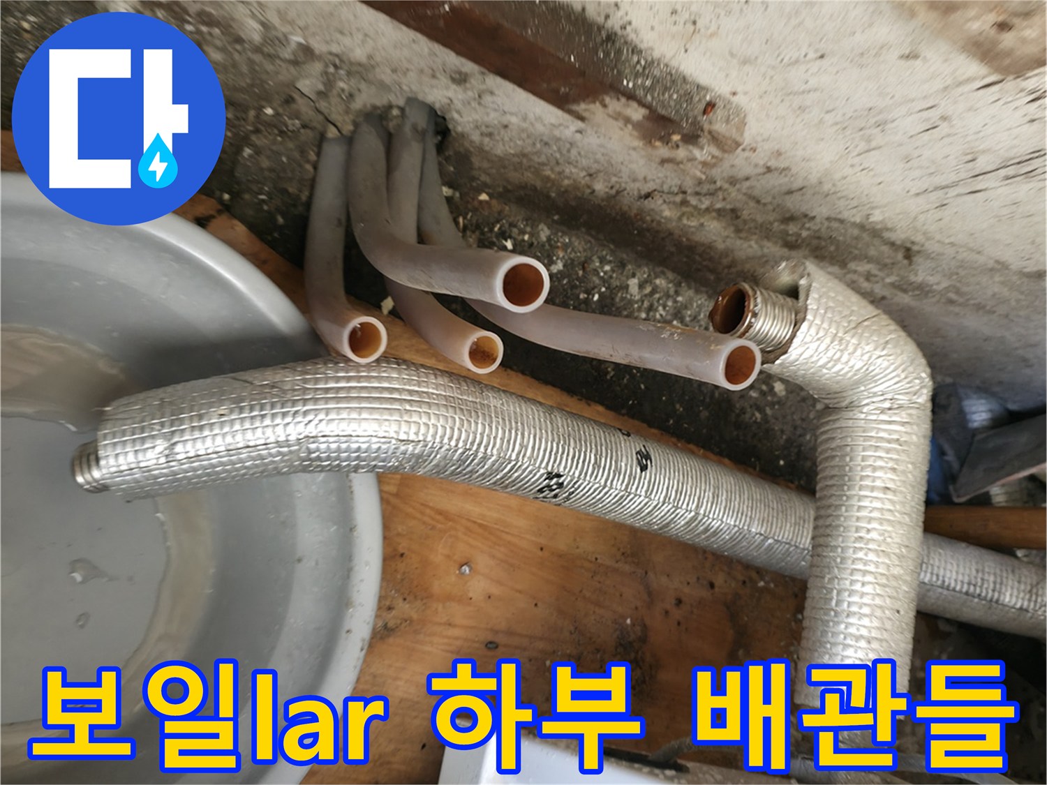 보일러 아래쪽의 은색 보온재 배관과 분기된 엑셀 관들의 근접 촬영입니다.