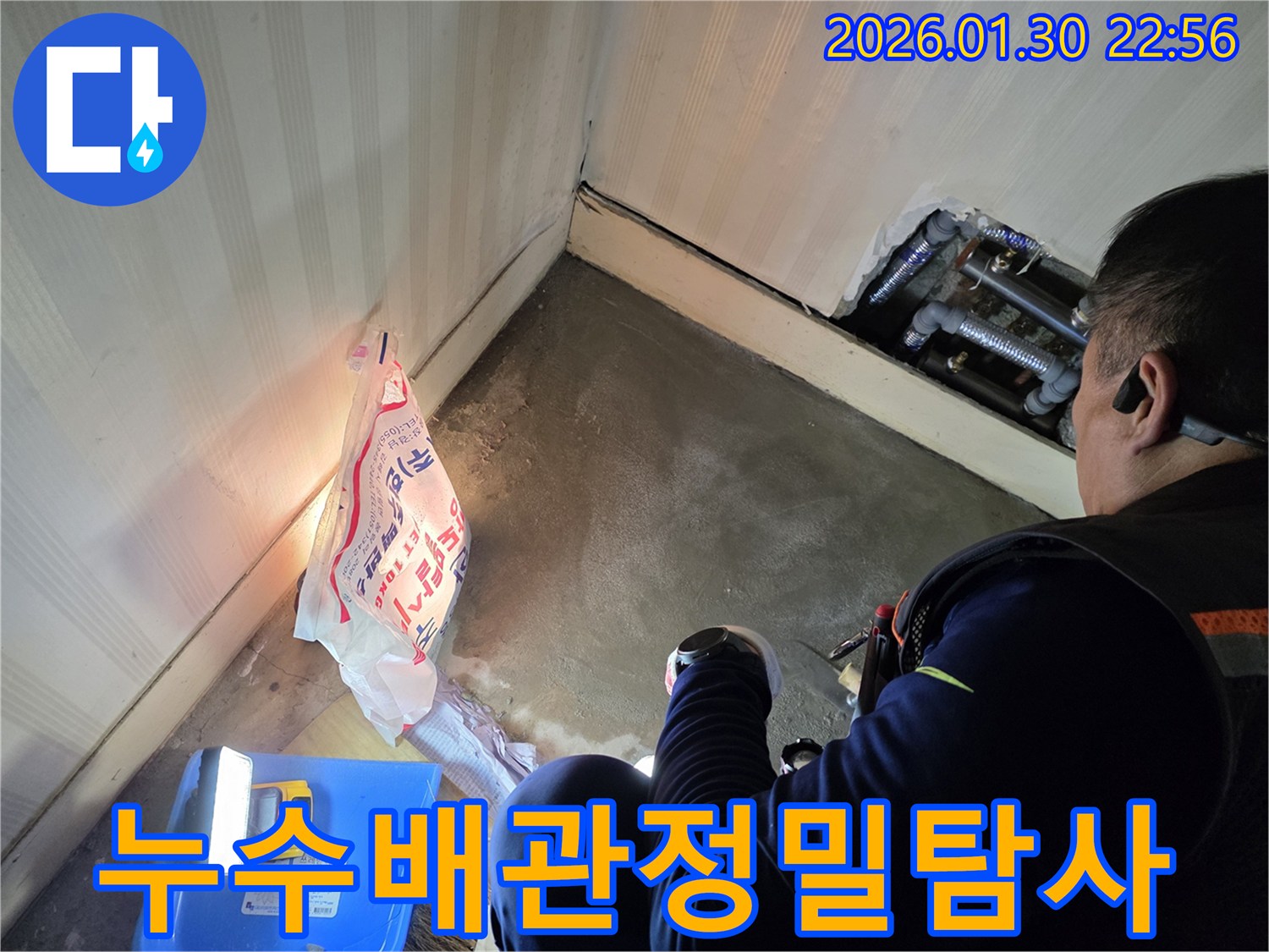 누수-전문가가-어두운-틈새에-있는-배관을-조명으로-밝혀-누수-흔적을-찾아내는-장면입니다